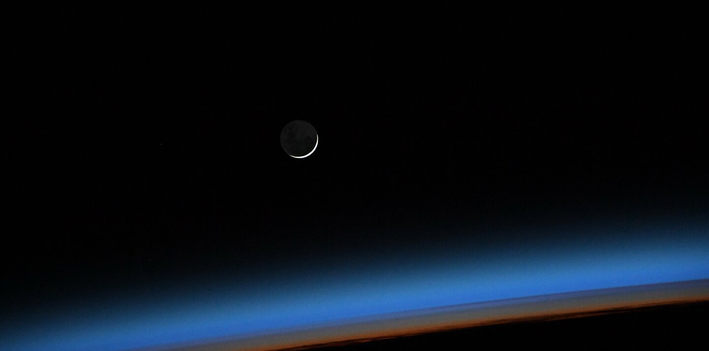 Ein aufgehender Neumond aufgenommen aus der International Space Station, zu erkennen ist die dünne Erdatmosphäre in blau und orange. | © ESA - S. Cristoforetti