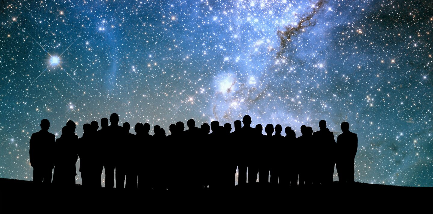 Personengruppe abgebildet vor dem Nachthimmel mit Sternen und Galaxien